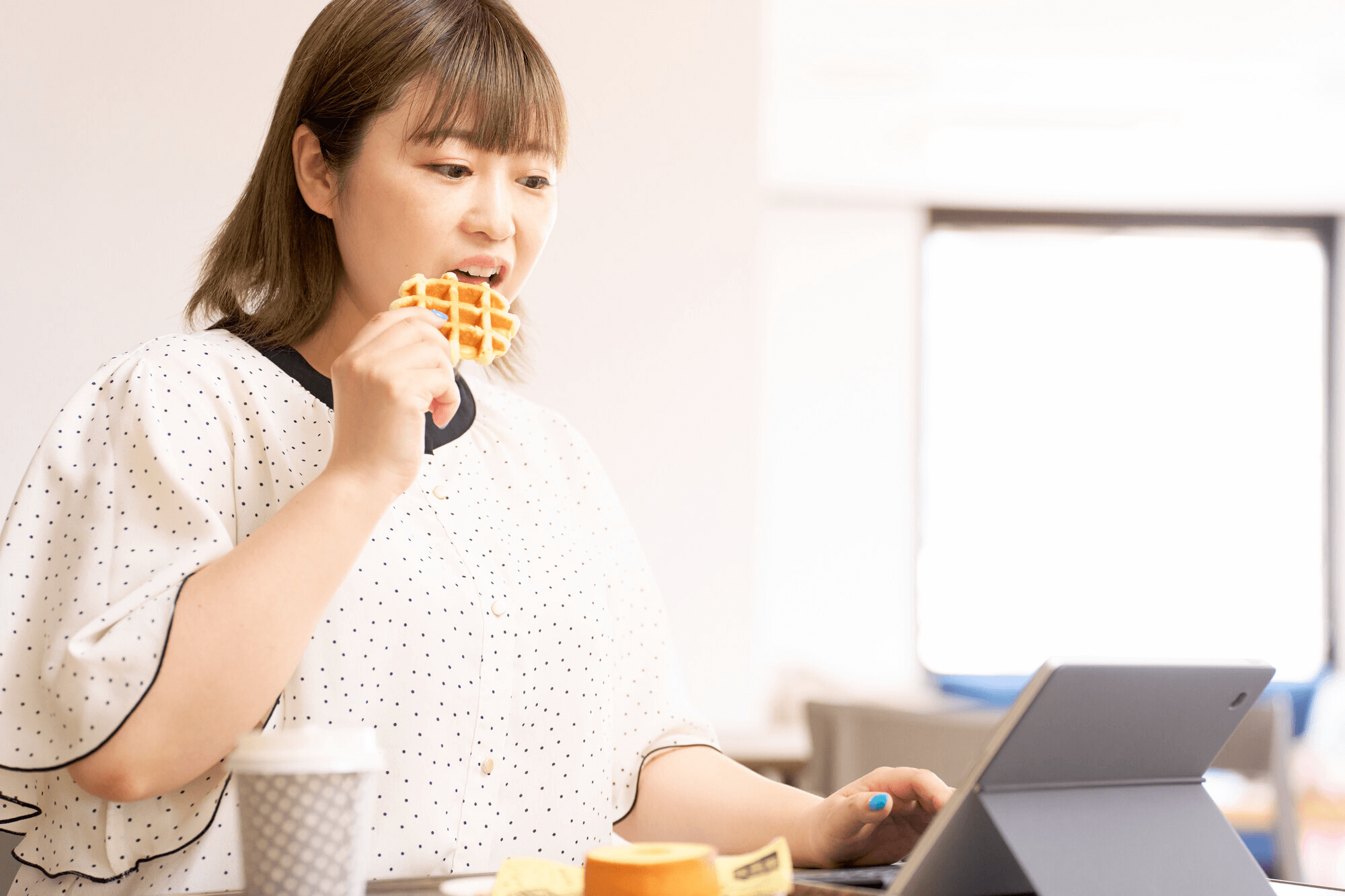 間食をやめるだけでも内臓脂肪は落とせる。ワッフルなど甘いスイーツを食べようとしている女性のイメージ写真。