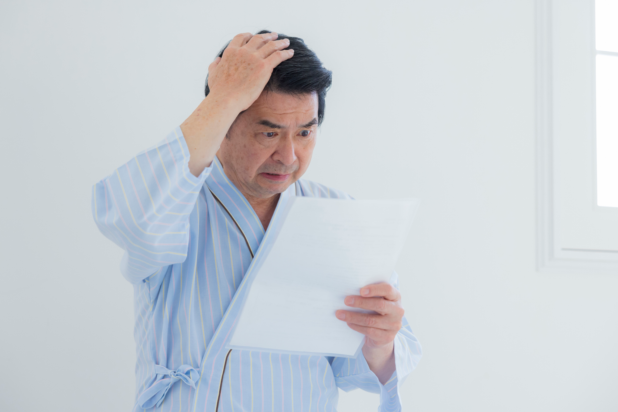 健康診断の結果を確認してショックを受ける男性のイメージ画像