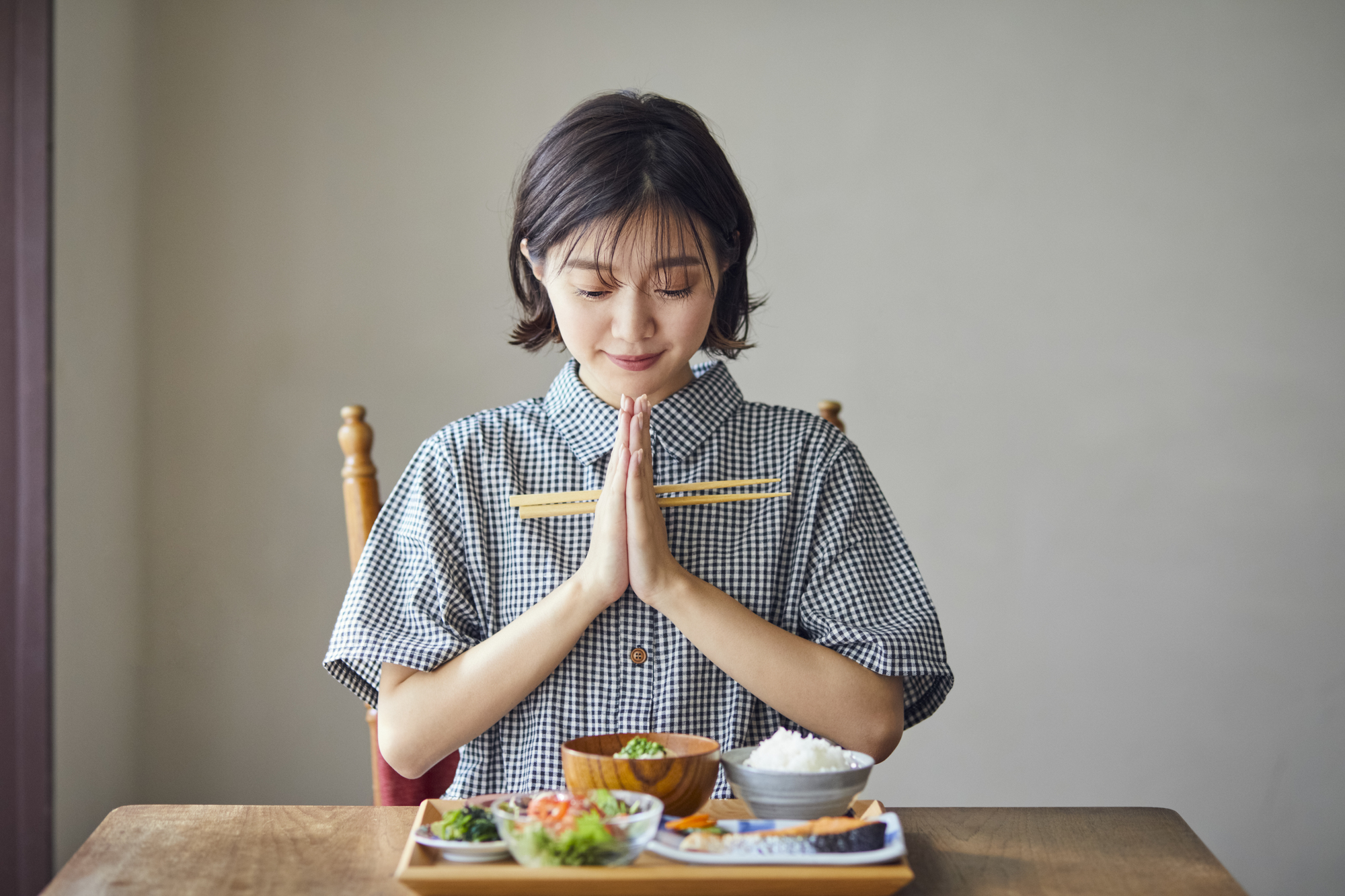 食事を前に手を合わせていただきますと言っている女性のイメージ写真