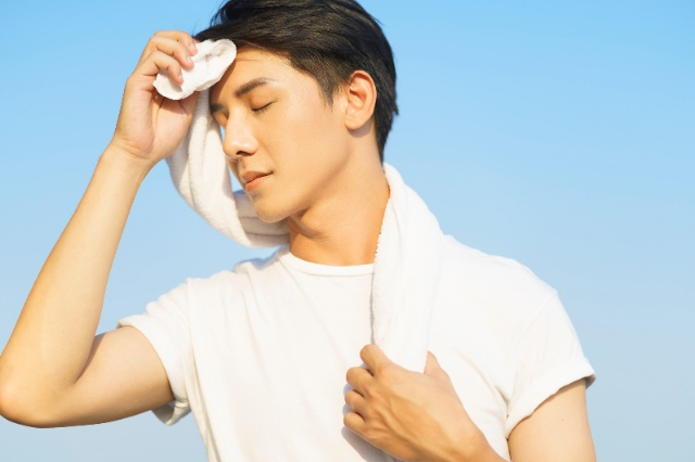 汗をぬぐう男性のイメージ画像